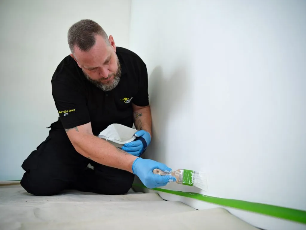Painter and decorator finishing an interior wall in Bury